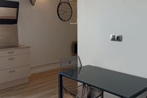 ein Esszimmer mit einem Glastisch und einer Uhr an der Wand in der Unterkunft Suresnes : 2 pièces cosy in Suresnes