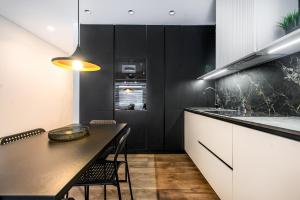 a black and white kitchen with a table and a counter at Botanical Garden Loft in Kaunas