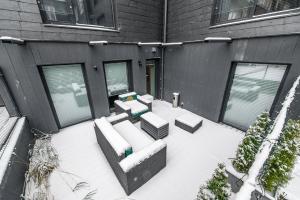 a snow covered patio with couches and tables in front of a building at Botanical Garden loft in Kaunas