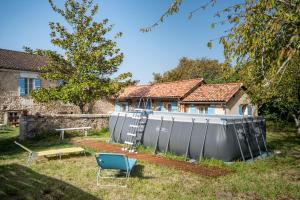 ein Haus mit einem Metallzaun im Hof in der Unterkunft Gîte de La Vieille Bécane in La Gonterie-Boulouneix