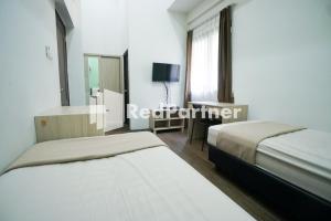 two beds in a room with a mirror and a tv at Toba Mansion Syariah near Benhil RedPartner in Jakarta