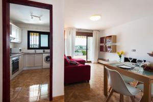 een keuken en een woonkamer met een rode bank en een tafel bij Peace & Golf - Mijas Duplex Apartment- Pets Friendly in Fuengirola