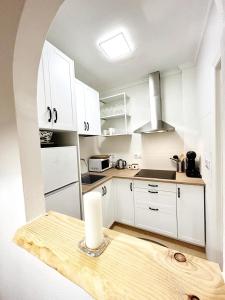 una cocina con armarios blancos y una vela sobre una mesa en Apartamentos Palangres, en Torrevieja