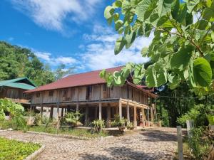 a wooden house with a red roof at Muong Bi Homestay - Uncle Lon - Luy Ai village in Hòa Bình