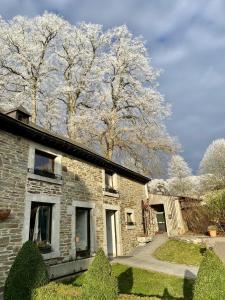 a stone house with trees in the background at Le Marronnier in La Roche-en-Ardenne