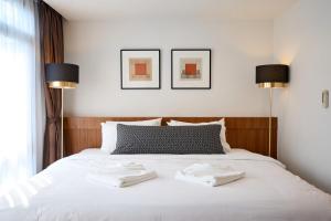 a bedroom with a white bed with two towels on it at Be Phrasingh Hotel Chiang Mai in Chiang Mai