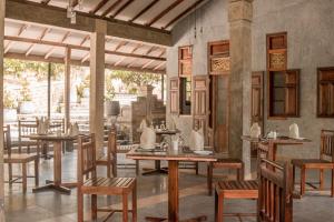 a dining room with wooden tables and chairs at The Coastal Village Cabanas in Galle