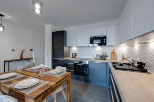 cocina con mesa de madera y armarios azules en Le Paradis - Beautiful T2 ideally located with garage en Annecy