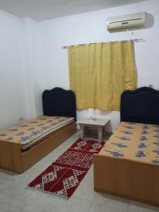 two beds in a room with a window and a rug at Appartamento con piscina Santa Maria area in Hurghada
