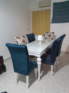 a dining room table with blue chairs and a white table at Appartamento con piscina Santa Maria area in Hurghada