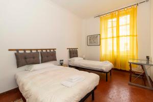 a bedroom with two beds and a table and a window at Mercato Centrale Roomy Apartment in Turin