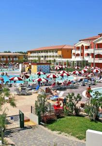 a pool with umbrellas and people in a resort at Pini Village Lido Altanea in Caorle