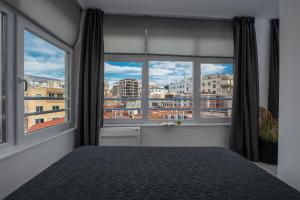 ein Schlafzimmer mit einem Bett und zwei großen Fenstern in der Unterkunft Nomades Suites in Thessaloniki