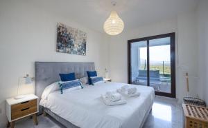 sypialnia z dużym białym łóżkiem i niebieskimi poduszkami w obiekcie Alcaidesa Golf and Beach 2356 w mieście La Alcaidesa