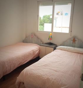two beds in a small room with a window at Amplio, luminoso, moderno in Calasparra