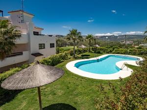 einen externen Blick auf eine Villa mit einem Pool und einem Sonnenschirm in der Unterkunft Lotus 2401 - Beautiful apartment with pool & sea view in Casares