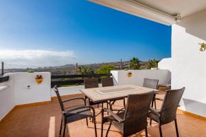 patio con mesa y sillas en el balcón en Lotus 2401 - Beautiful apartment with pool & sea view, en Casares