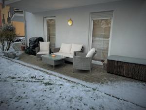 a patio with a couch and chairs in the snow at Apartment Fulda Aue in Fulda