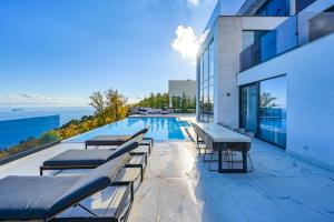 a swimming pool with tables and chairs next to a building at Villa Naya with Heated Pool and Hot Tub in Veprinac