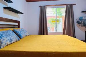 1 dormitorio con 1 cama grande de color amarillo y ventana en Casa de Huéspedes en Playas de Oro. en Villa Carlos Paz