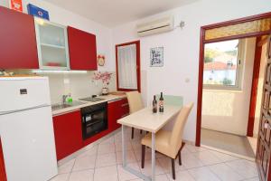 uma cozinha com armários vermelhos e uma mesa com cadeiras em Seafront Apartments Anthony em Lastovo