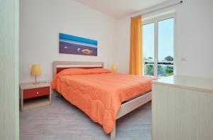 1 dormitorio con cama con colcha de color naranja y ventana en Case Vacanze Pomelia, en Marina di Ragusa
