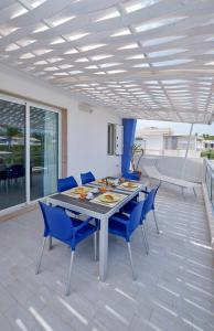un patio con sillas y mesa de comedor y sillas azules en Case Vacanze Pomelia, en Marina di Ragusa