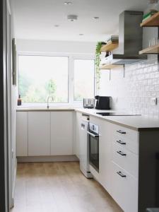 a white kitchen with a sink and a stove at The Palm House Falmouth - minutes from the beach! in Falmouth