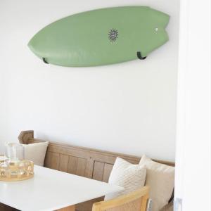 a surfboard hanging over a table with a white table sidx sidx sidx at The Palm House Falmouth - minutes from the beach! in Falmouth