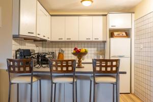 a kitchen with white cabinets and a counter with chairs at Bayview Studio in Kritharia