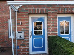 a brick house with a blue door and a window at Ferienwohnung Zweite Heimat 45248 in Ditzum