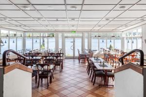 een restaurant met tafels, stoelen en ramen bij Hotell Frykenstrand; Sure Hotel Collection by Best Western in Sunne