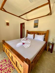a large wooden bed with two towels on it at Lala salama Kendwa villas in Kendwa