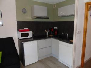 eine kleine Küche mit weißen Schränken und einer Mikrowelle in der Unterkunft Studio Modane, 1 pièce, 4 personnes - FR-1-561-100 in Modane