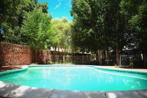 a swimming pool with blue water in front of a fence at Kroon Manor in Kroonstad