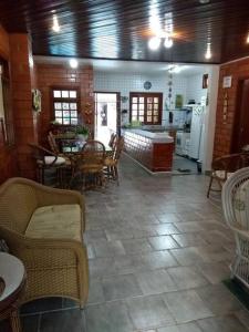 a living room with tables and chairs and a kitchen at Casa praia Camburi com piscina in Camburi