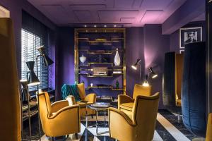 a room with chairs and a table and purple walls at The Tribune, part of JdV by Hyatt in Rome