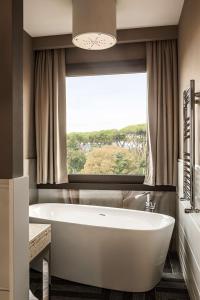 a bathroom with a tub and a large window at The Tribune, part of JdV by Hyatt in Rome