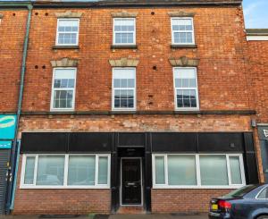 a red brick building with a black door at Cozy and Quirky Central Derby Apartments in Derby