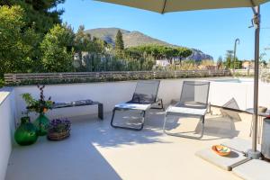 eine Terrasse mit 2 Stühlen und einem Sonnenschirm in der Unterkunft Domìa Boutique Hotel e Cucina in Mondello