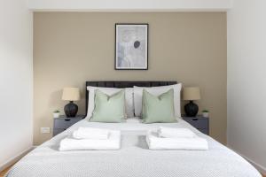 a white bedroom with a large bed with green pillows at The Camberwell Apartment in London