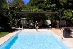 a woman in a bikini walking into a swimming pool at Domìa Boutique Hotel e Cucina in Mondello