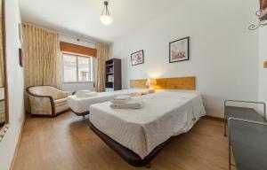 una habitación de hotel con 2 camas y una silla en O - São Gonçalo Central Guesthouse en Lagos
