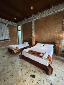 a bedroom with two beds and a brick wall at OHEI in Tangalle