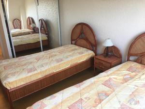sypialnia z 2 łóżkami i stolikiem nocnym z lustrem w obiekcie Appartement Fort-Mahon-Plage, 3 pièces, 4 personnes - FR-1-482-5 w mieście Fort-Mahon-Plage