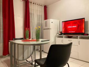 cocina con mesa, TV y cortinas rojas en Studio calme et éclairé proche de Nation C en París