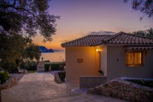 a house with a sunset in the background at Marathia Cottages Zakynthos in Marathias