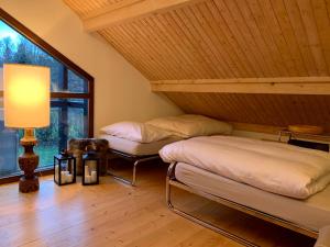 two beds in a room with a lamp and a window at Unique Sustainabel Lodge in the Swiss Jura Mountains in Neuchâtel