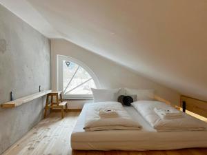 uma cama branca num quarto com uma grande janela em Gmunder Premium Dachgeschoss-Apartments em Gmund am Tegernsee