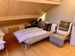 Cette chambre mansardée comprend un lit et une chaise. dans l'établissement Unique Sustainabel Lodge in the Swiss Jura Mountains, à Neuchâtel